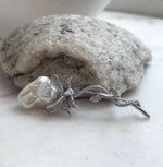 White baroque pearl with rainbow reflections in a crystal-accented floral brooch.