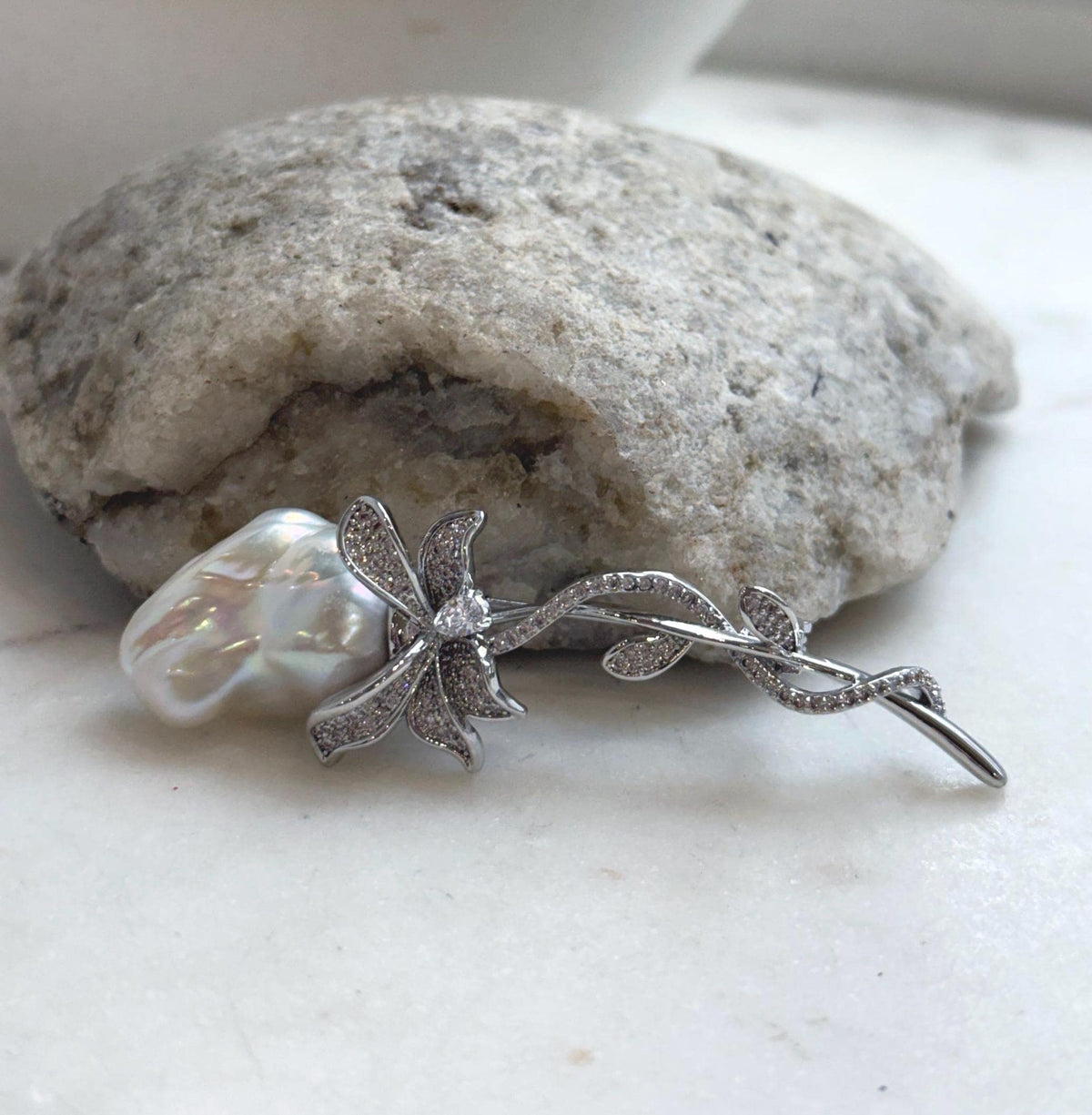 White baroque pearl with rainbow reflections in a crystal-accented floral brooch.