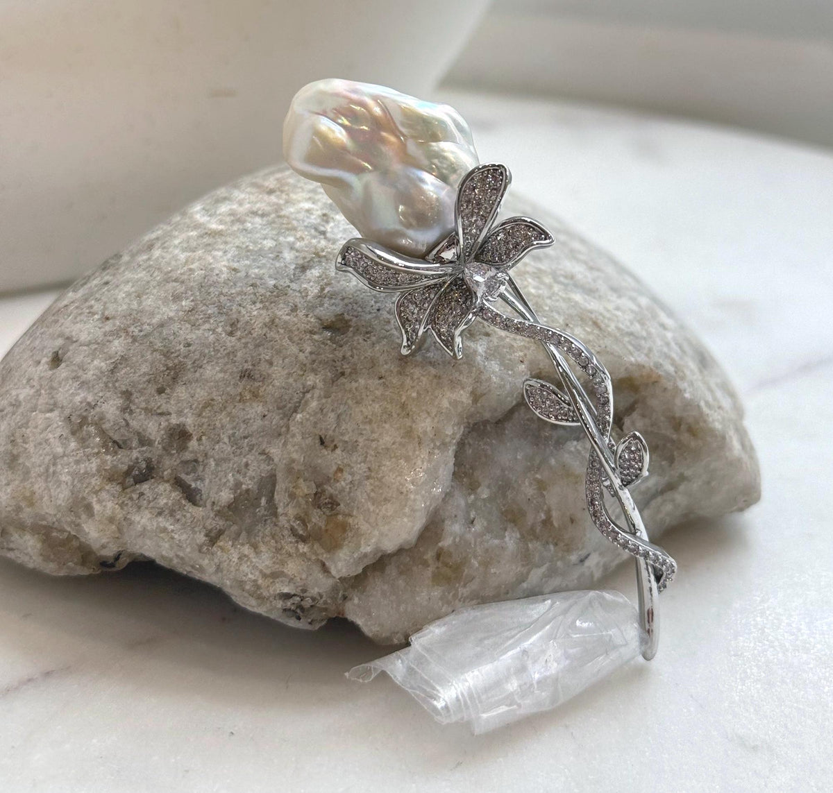 Silver-tone vine brooch showcasing an organically shaped white baroque pearl.