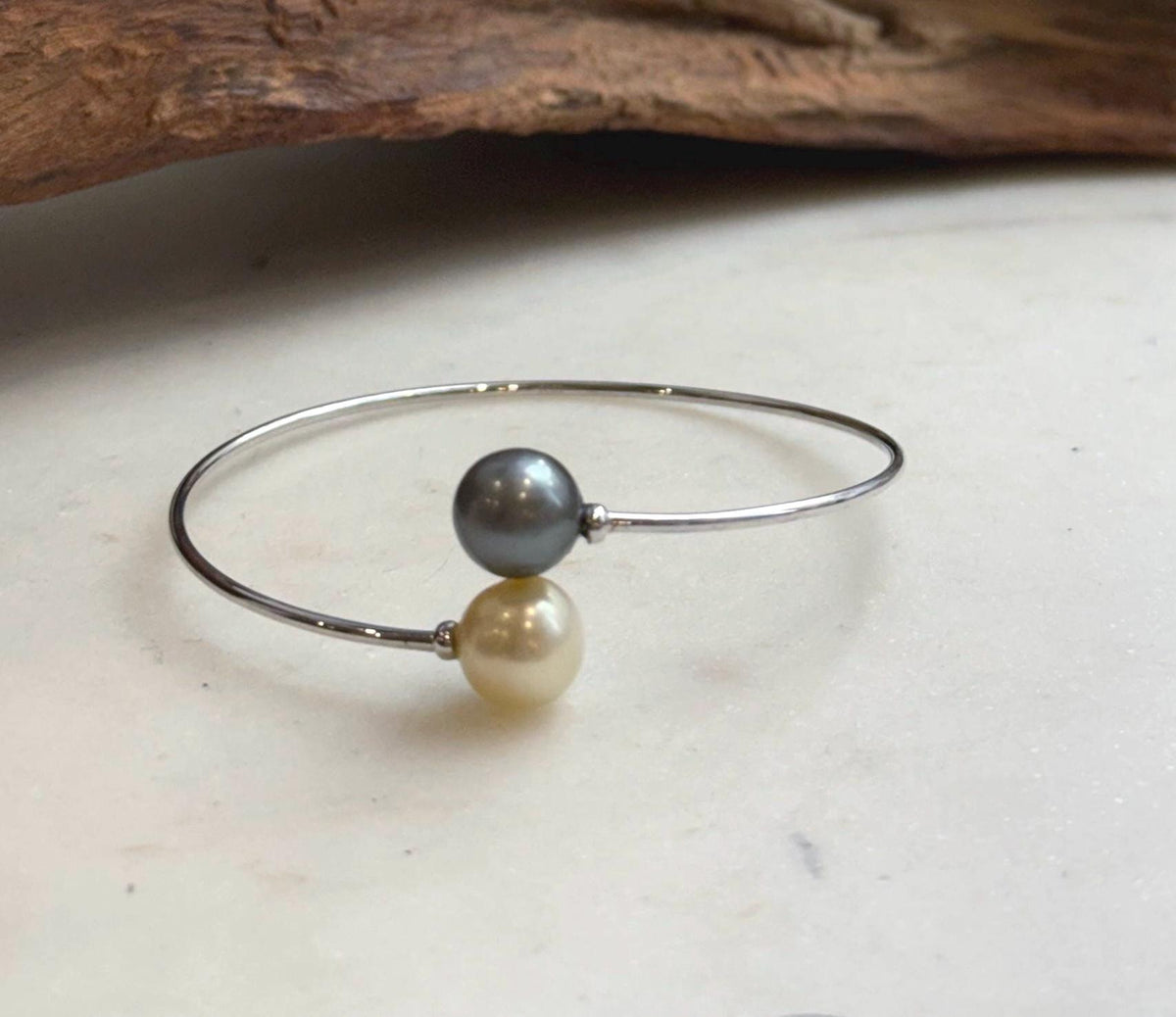 Champagne gold ocean pearl paired with a platinum gray pearl on a silver bracelet.