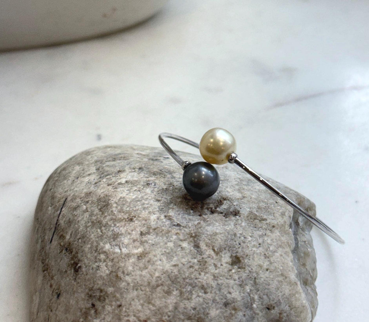 Two lustrous ocean pearls accent a slender sterling silver bangle.