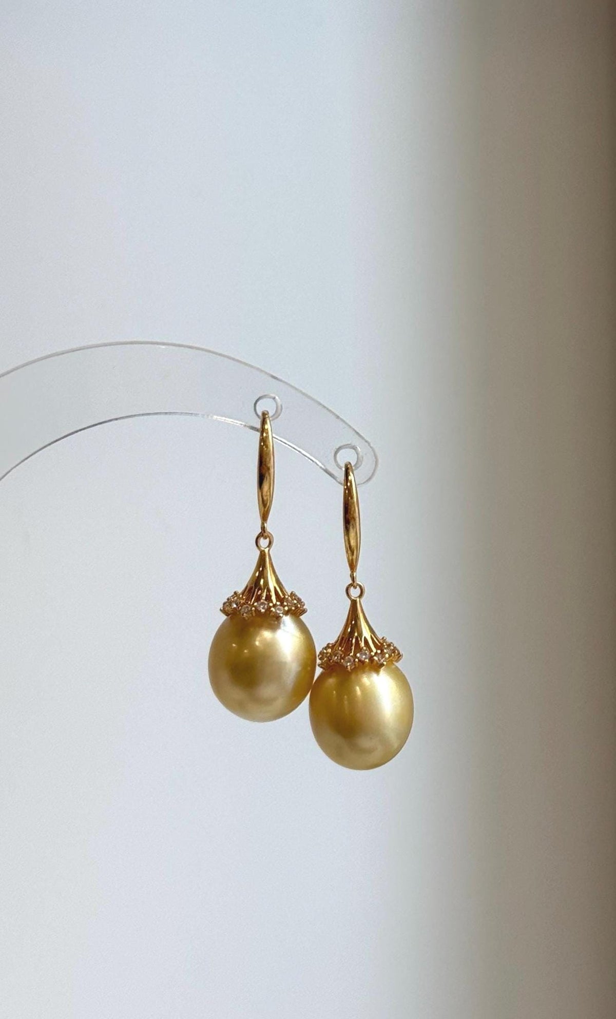 South Sea pearl earrings featuring rounded golden pearls and ornate gold-tone details.