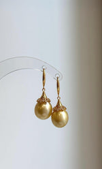 South Sea pearl earrings featuring rounded golden pearls and ornate gold-tone details.