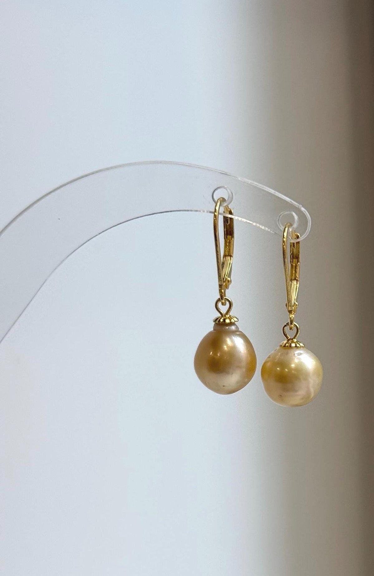 Champagne pearl earrings with hinged leverback closures and polished gold-tone details.