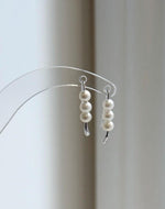 White triple pearl earrings with minimalist curved S925 sterling silver hooks.
