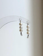 Three lustrous white pearls arranged vertically on each silver earring.