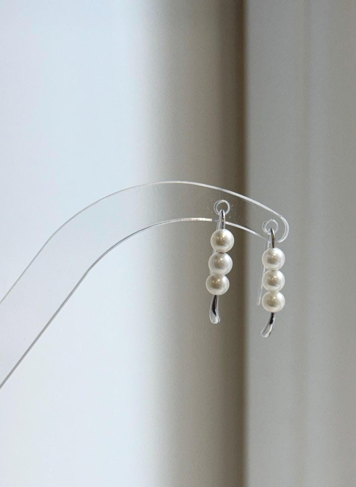 Triple pearl hook earrings with polished silver tips extending below the pearls.