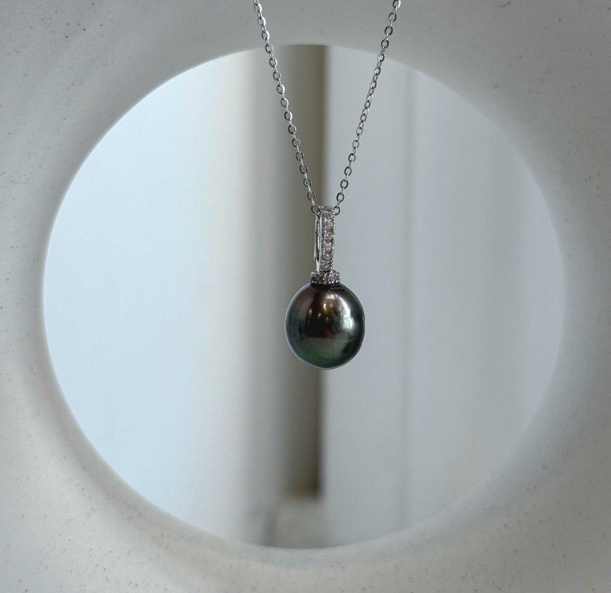 Crystal-accented silver pendant showcasing a lustrous peacock green Tahitian pearl.