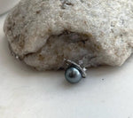 Dark green-gray Tahitian pearl encircled by a tilted sterling silver ring in a Saturn-inspired necklace.