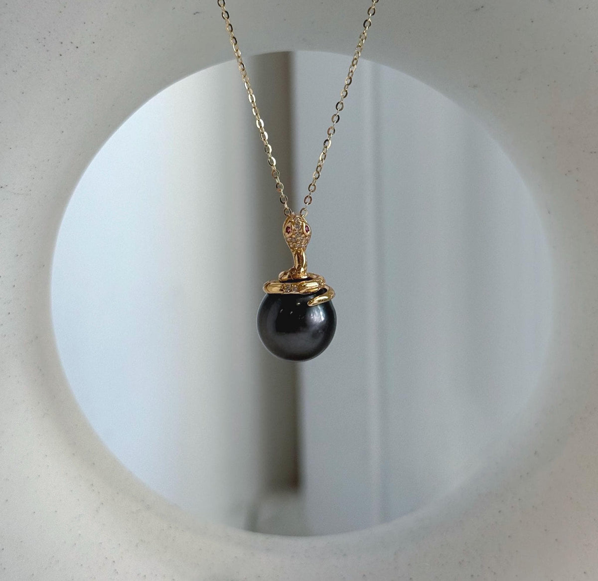 Genuine Tahitian saltwater pearl framed by a curved gold-tone snake design.