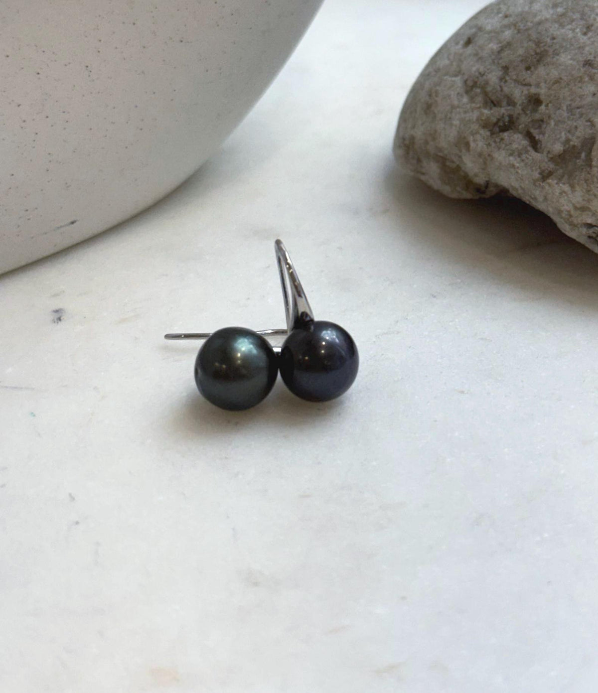 Dark pearl earrings showing reflective surfaces and subtle color variations.