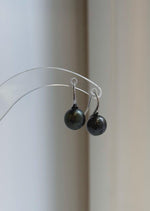 Round dark pearl drop earrings with polished sterling silver hooks.