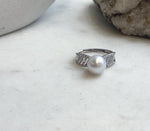 White South Sea pearl ring displayed on the rim of a cream ceramic vase.