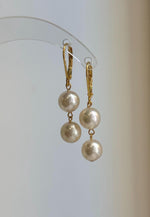 Rounded Akoya pearls suspended in a simple two-pearl dangle design.