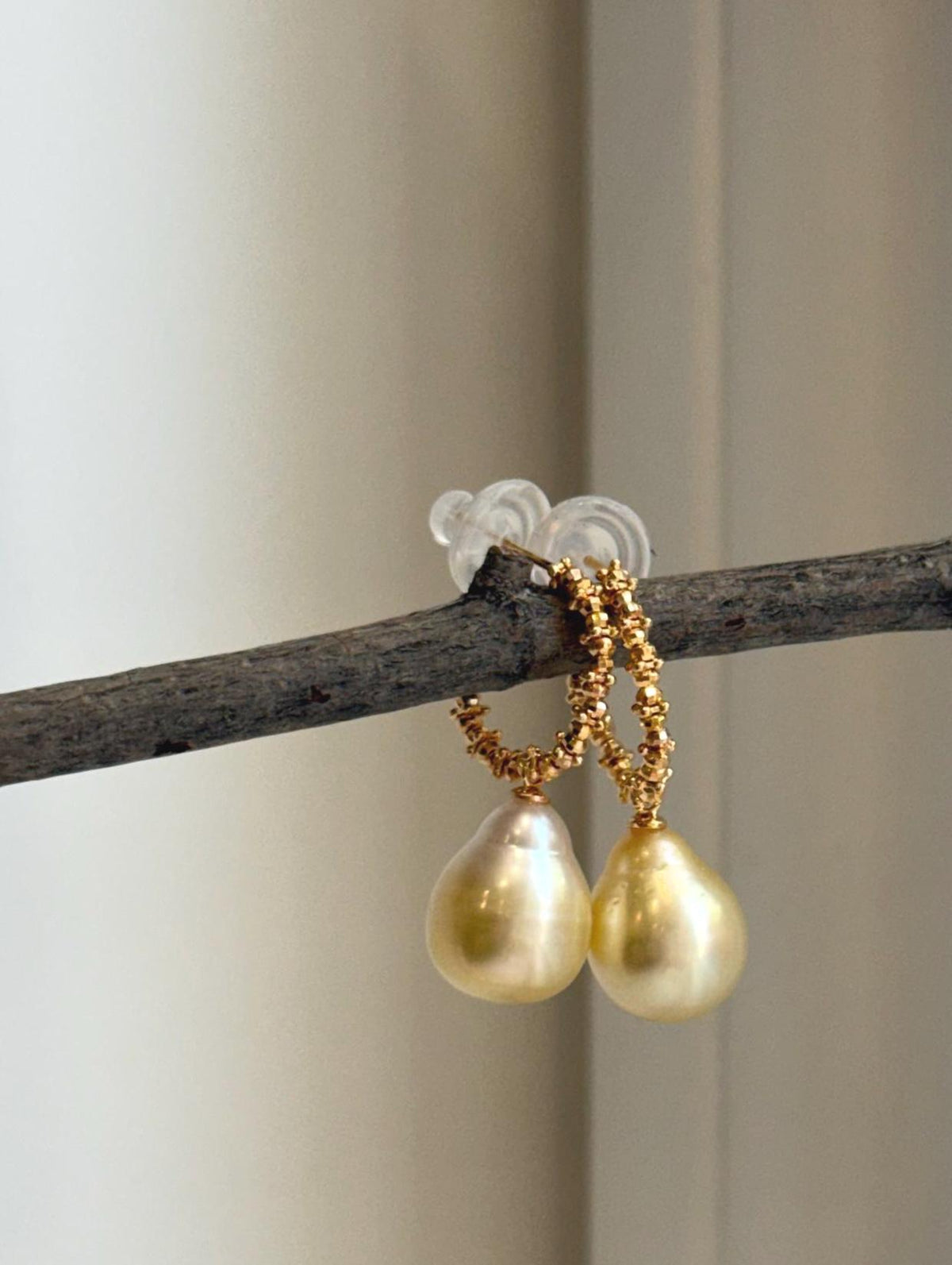 Golden saltwater pearl earrings with a highly reflective surface.
