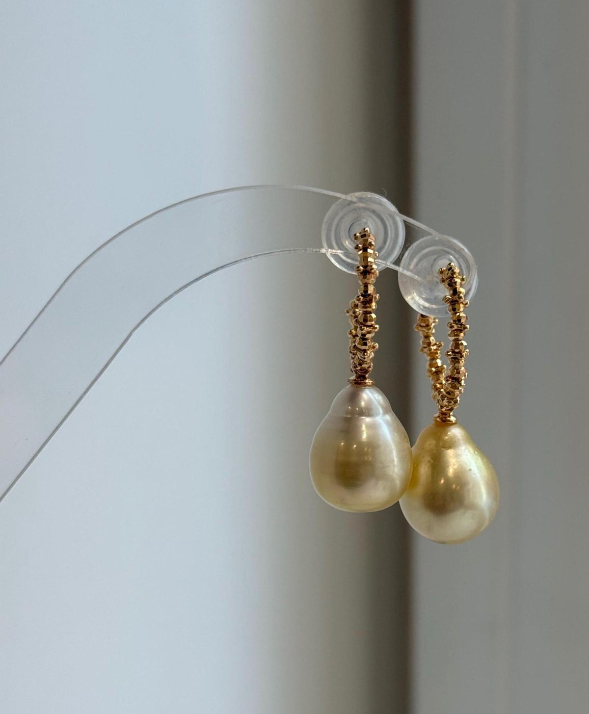 Golden saltwater pearl earrings with a highly reflective surface.