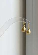 Lustrous golden South Sea pearl earrings hanging from a natural branch.