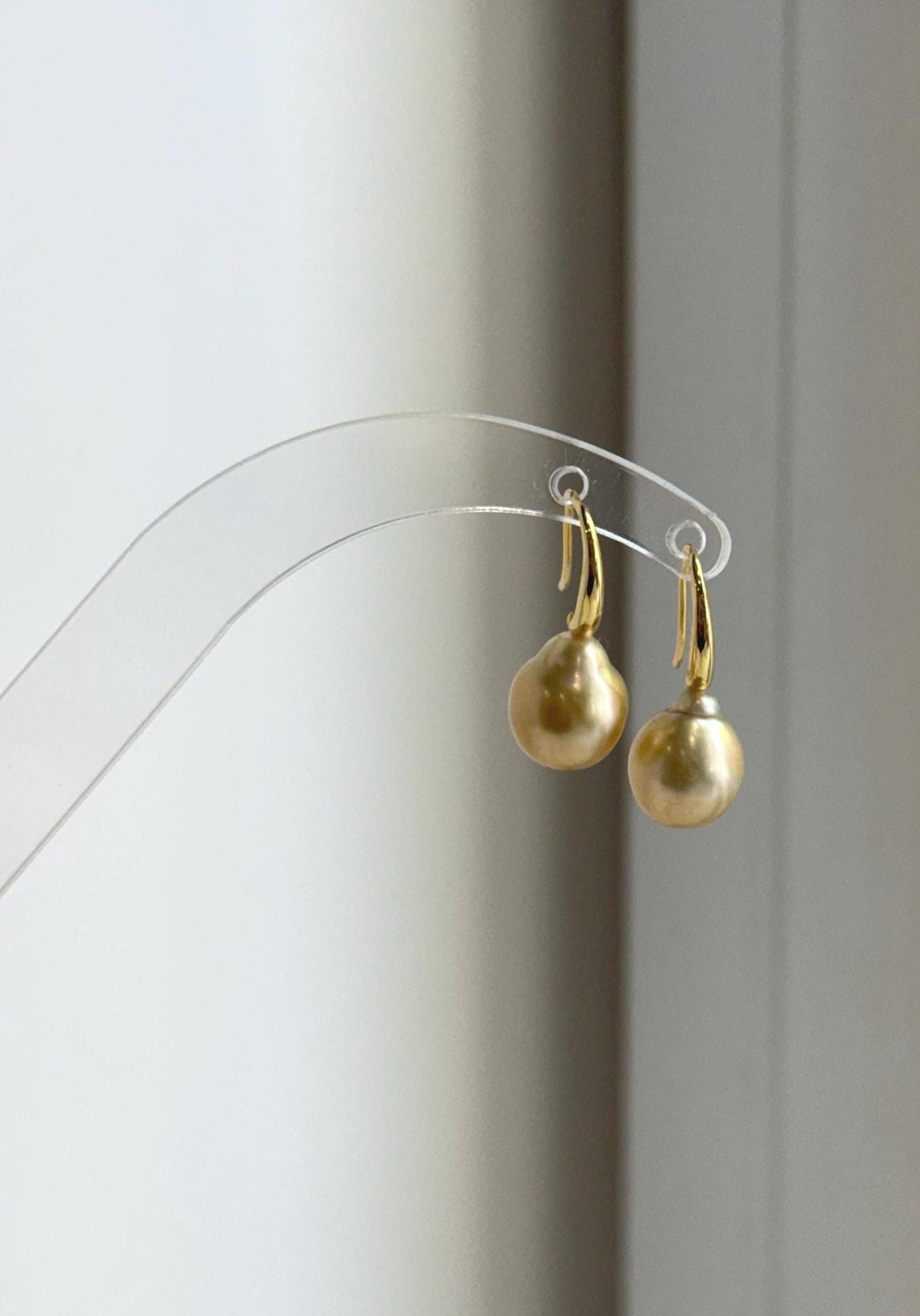 Lustrous golden South Sea pearl earrings hanging from a natural branch.