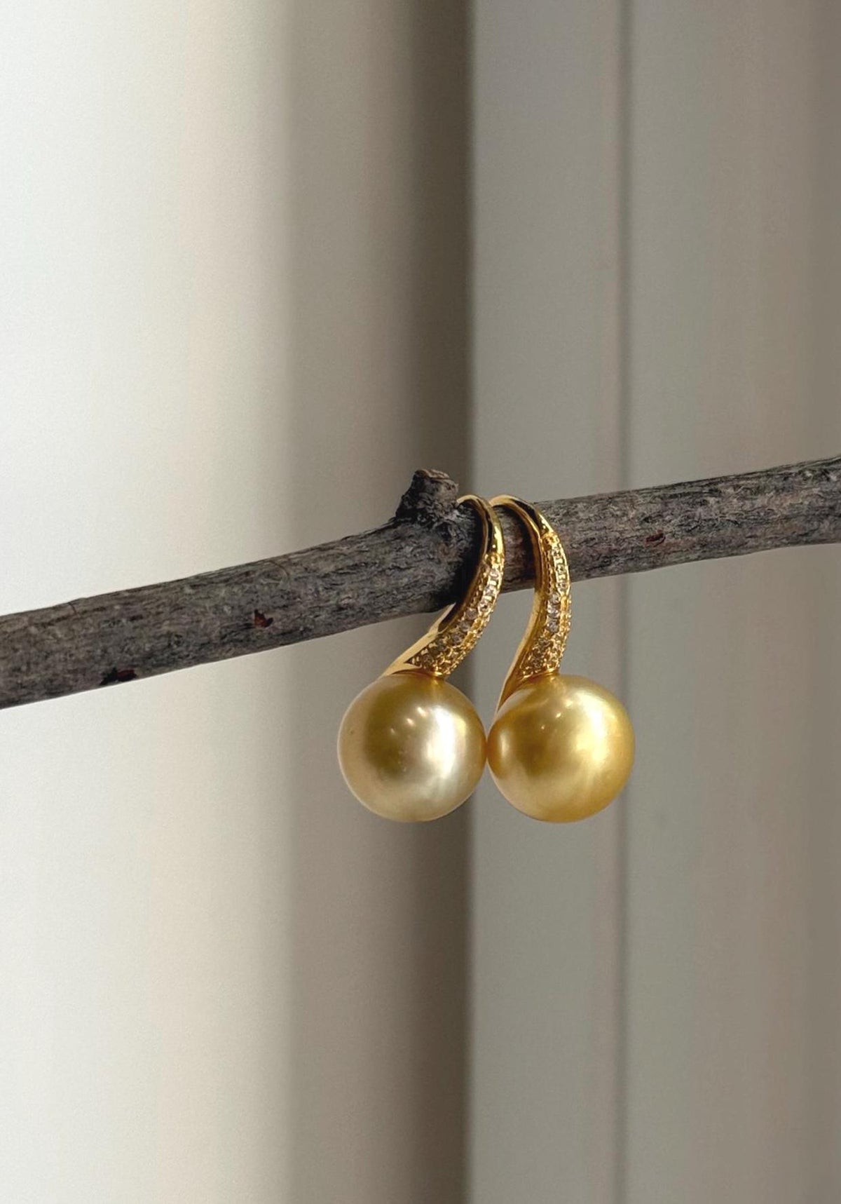 Golden pearl drop earrings with distinctive high-heel style hooks.