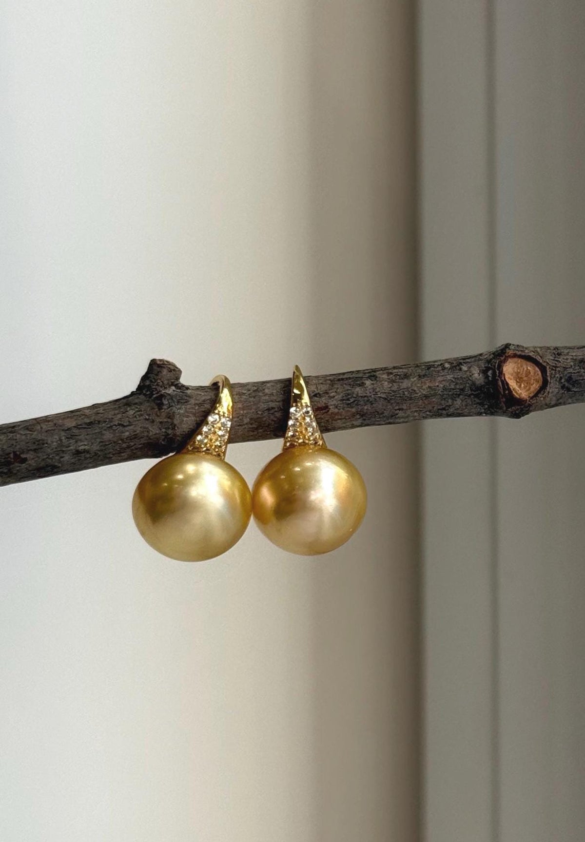 Deep tea gold pearl drop earrings with bright reflective luster.