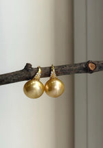 Deep tea gold pearl drop earrings with bright reflective luster.