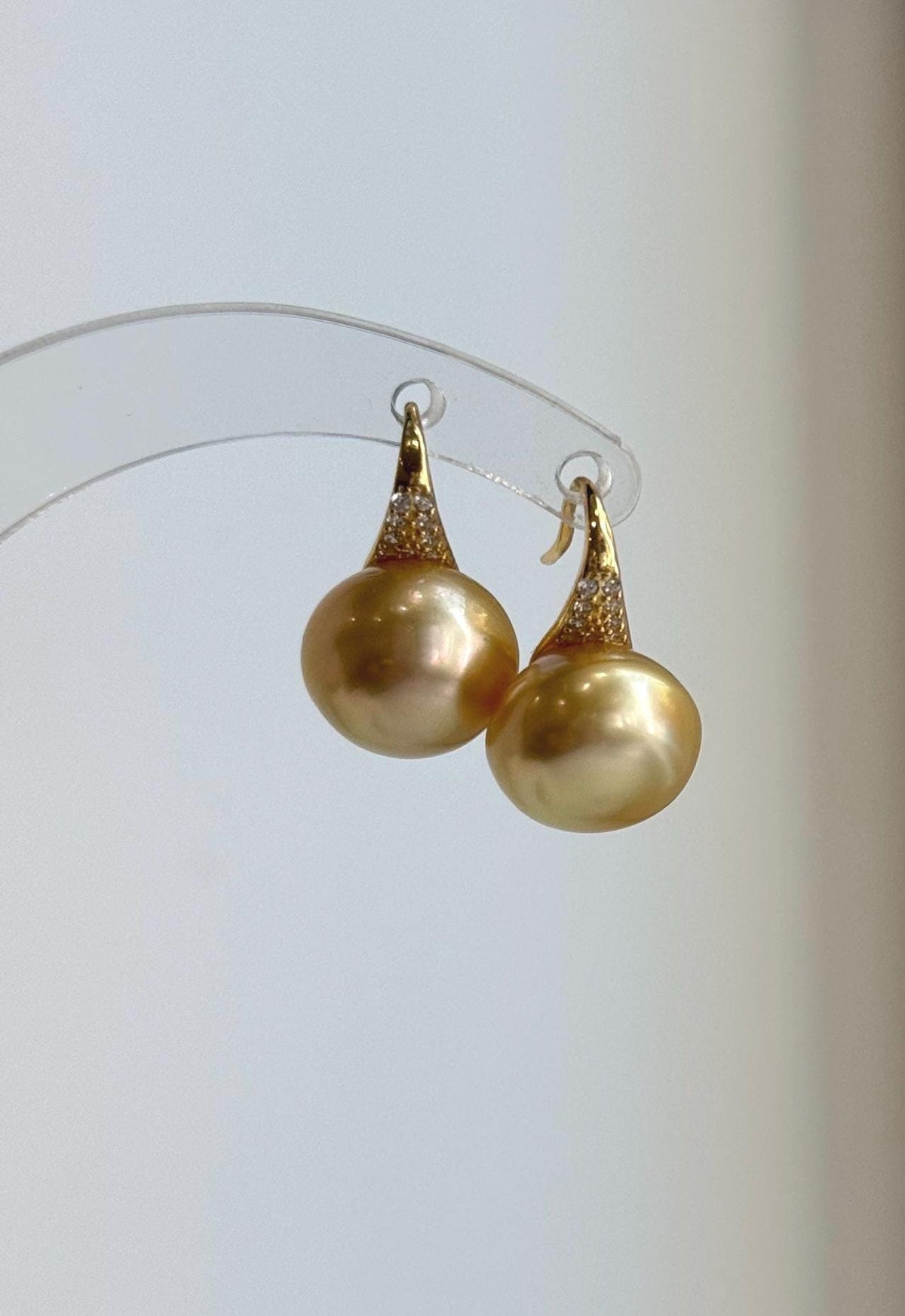 Golden South Sea pearl earrings combining reflective pearls and high-heel style silver hooks.