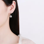 S925 sterling silver earrings featuring round moissanite centers surrounded by flower-shaped halos.