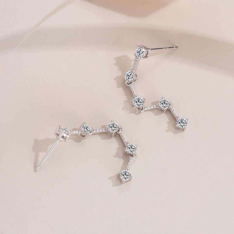 Long moissanite earrings with five prong-set stones arranged in a delicate vertical line.