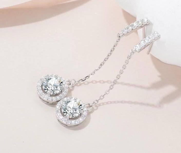 Long sterling silver earrings with delicate chains and circular moissanite halo drops.
