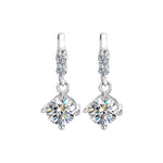 Sterling silver earrings featuring round moissanite drops beneath two smaller sparkling stones.