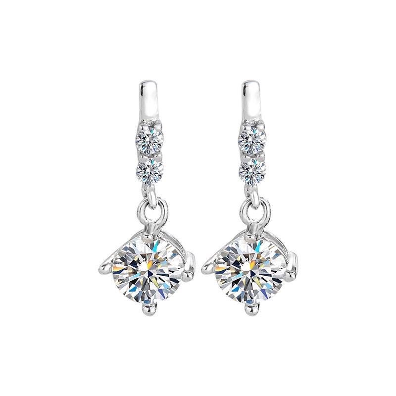 Sterling silver earrings featuring round moissanite drops beneath two smaller sparkling stones.