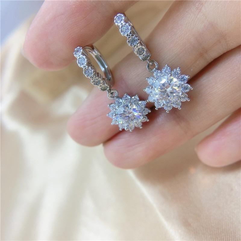 Sterling silver hoop earrings with sparkling stone accents and dangling flower-shaped halos.