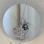 Peacock green pearl centerpiece nestled within a branching coral setting.