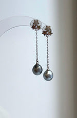Tahitian pearl star earrings displayed on a clear stand