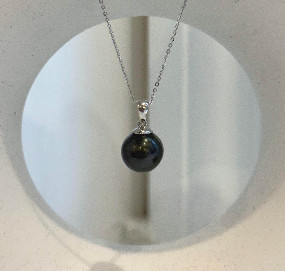 Black Tahitian ocean pearl pendant with a reflective surface and simple silver setting.