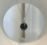 Tahitian pearl pendant with a dark body color and bright reflections across its surface.
