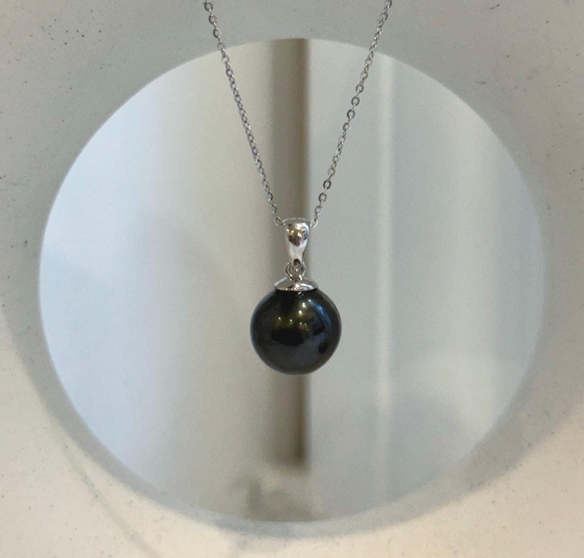 Tahitian pearl pendant with a dark body color and bright reflections across its surface.