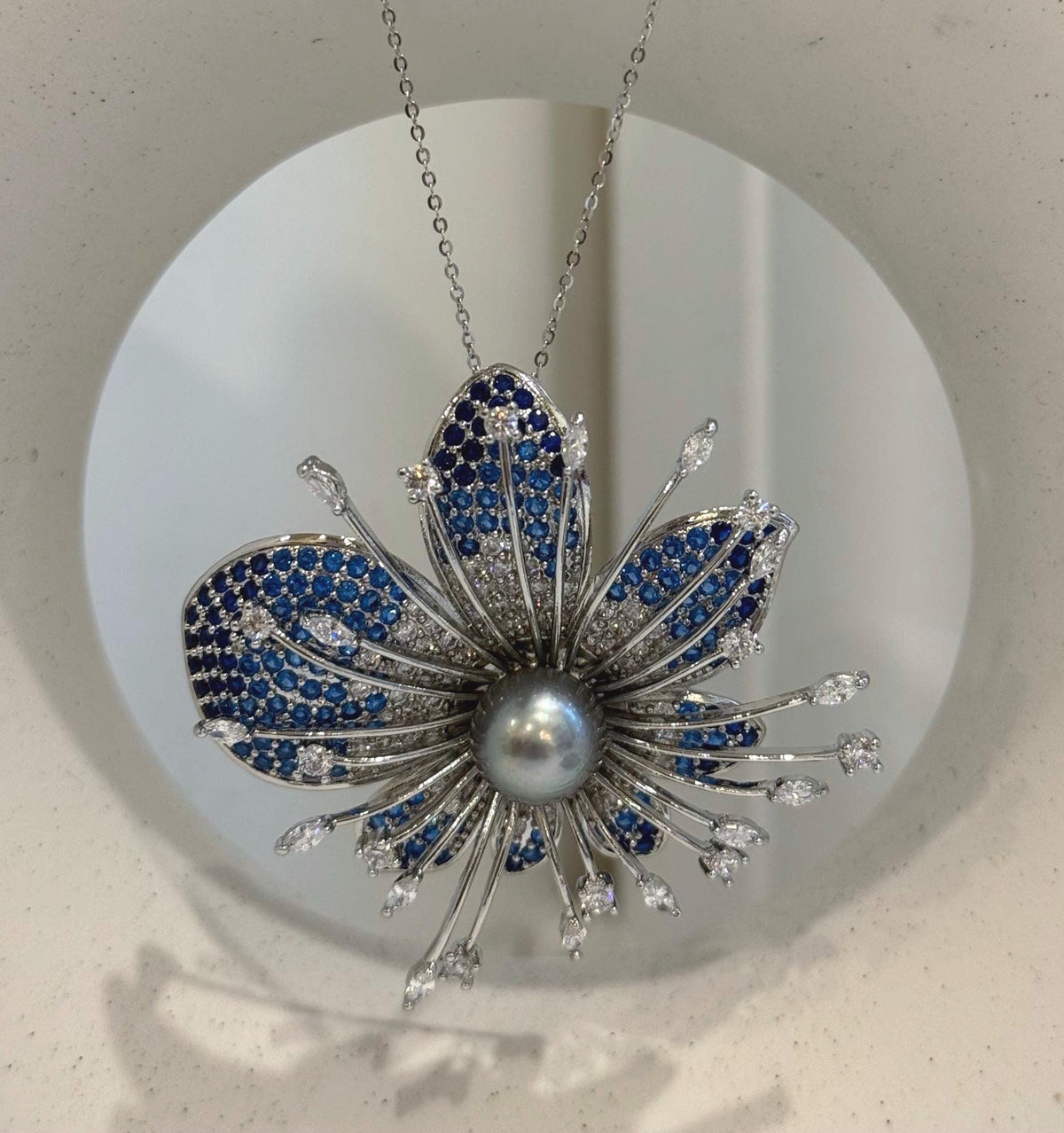 Blue flower brooch with curved petals and delicate silver-tone stems.