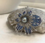 Lustrous gray pearl nestled among layered blue and clear floral petals.