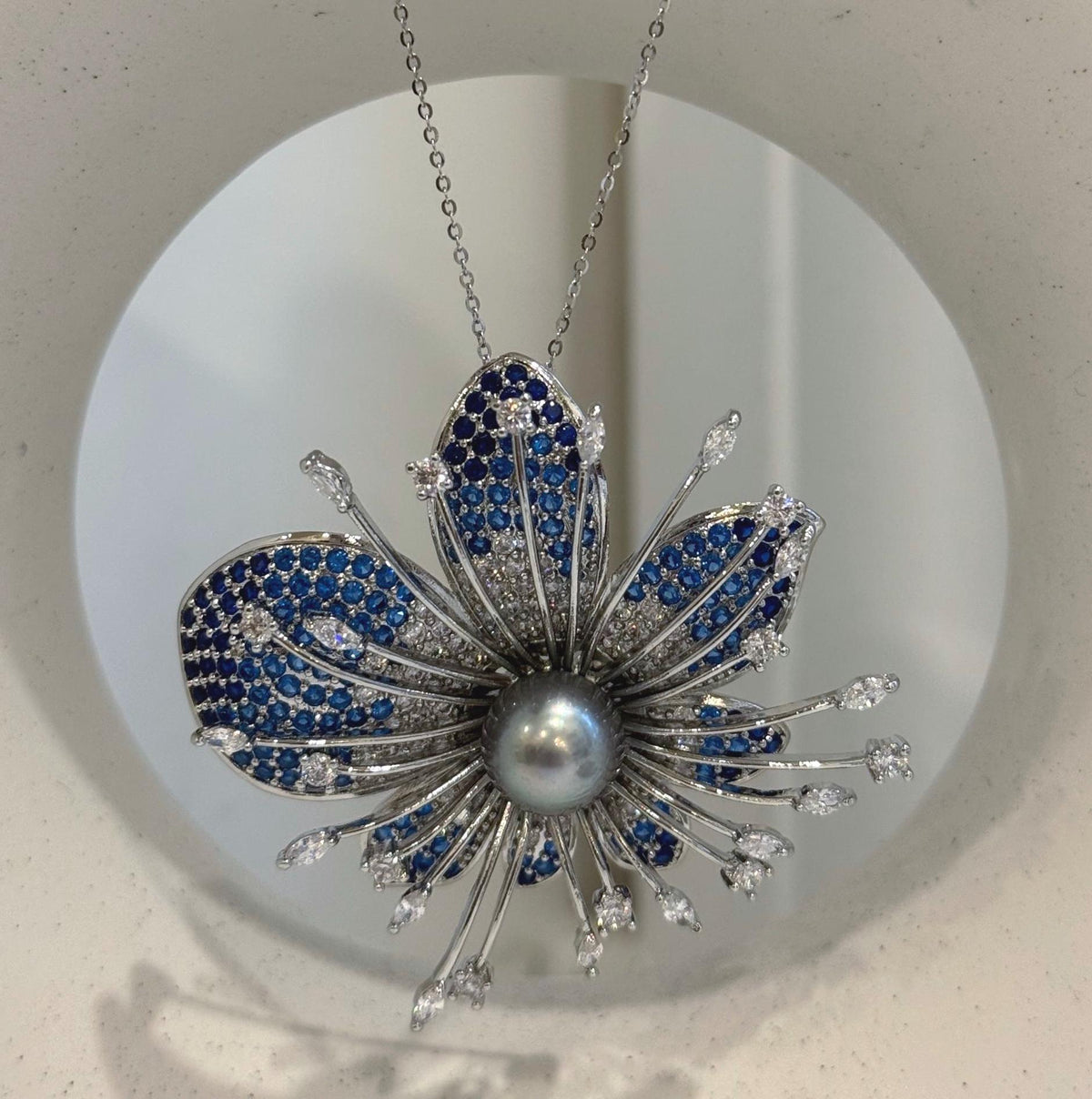 Decorative flower brooch with blue accents ranging from bright blue to navy.