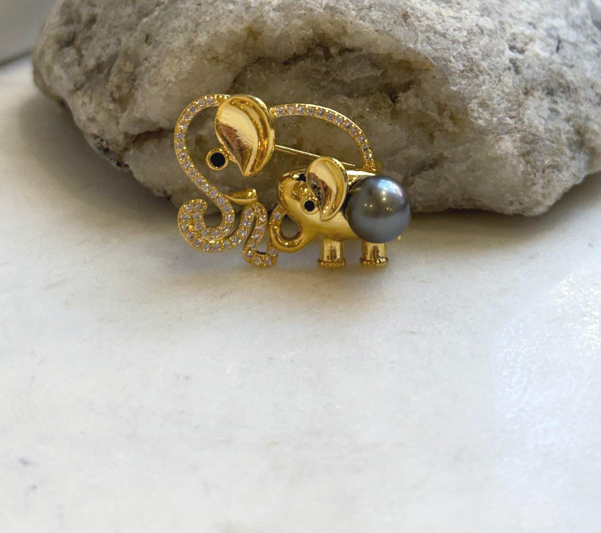 Dark gray Tahitian pearl forms the body of the baby elephant in this decorative brooch.