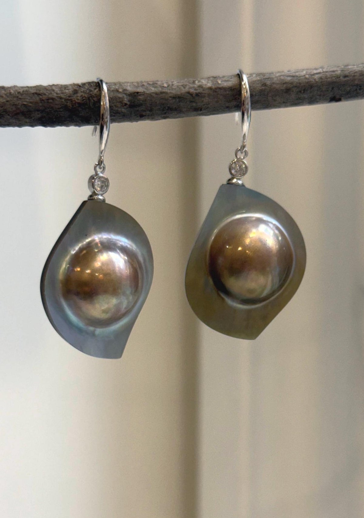 Golden mabe pearl earrings with rainbow overtones and mirror luster.