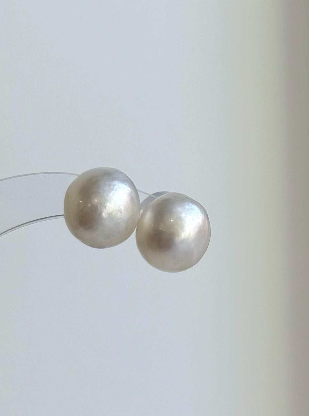White saltwater pearl studs featuring reflective surfaces and sterling silver settings.