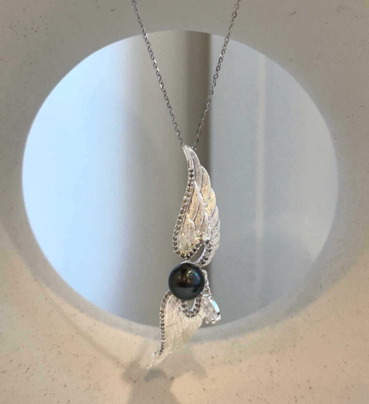 Angel wing brooch pendant featuring a lustrous dark green Tahitian saltwater pearl.