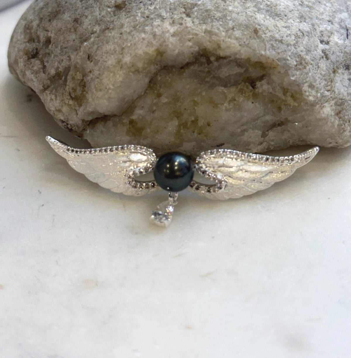 Two-in-one Tahitian pearl brooch and pendant with detailed feather wings.