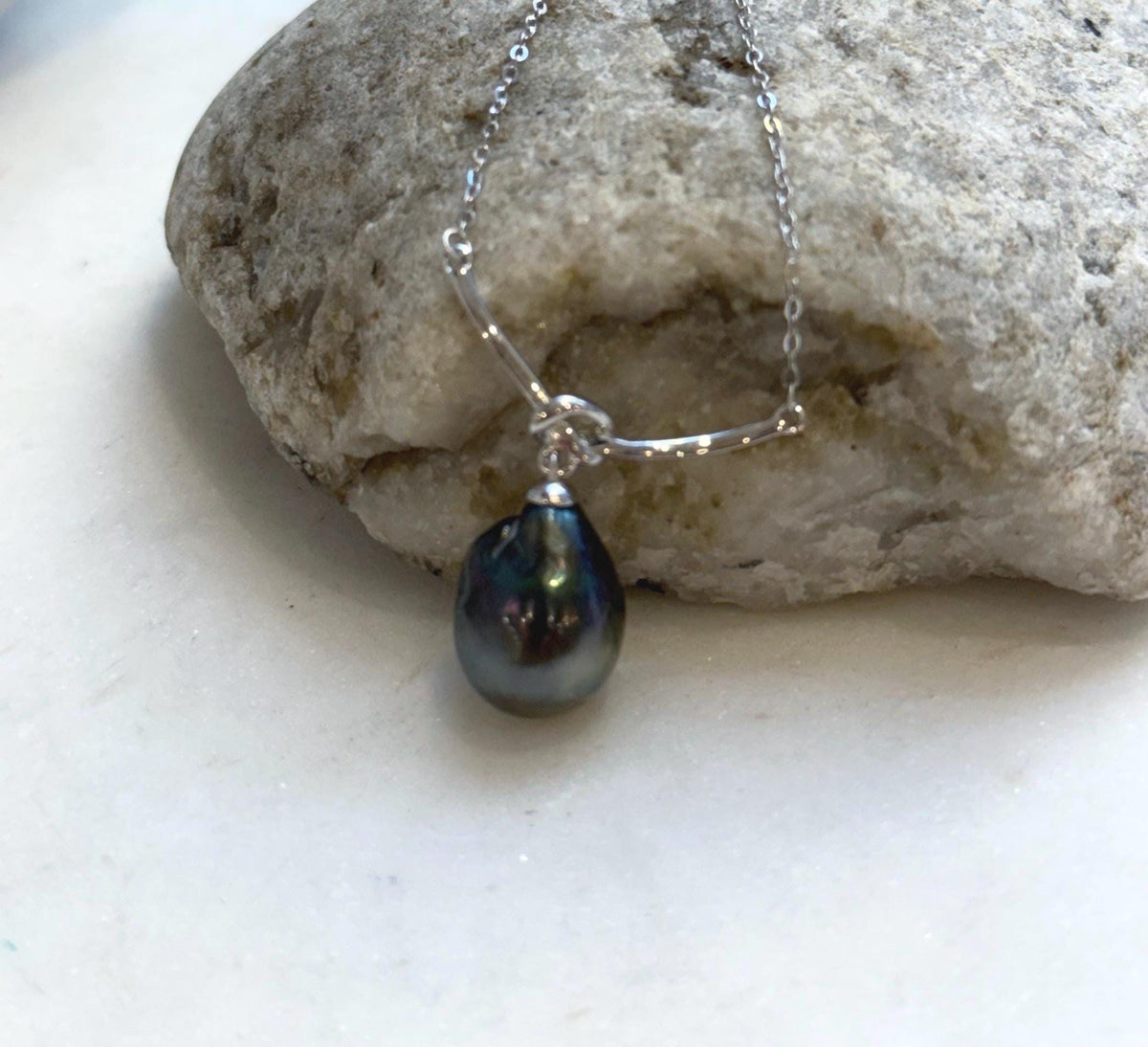 Dark Tahitian pearl pendant with colorful reflections and a curved sterling silver centerpiece.