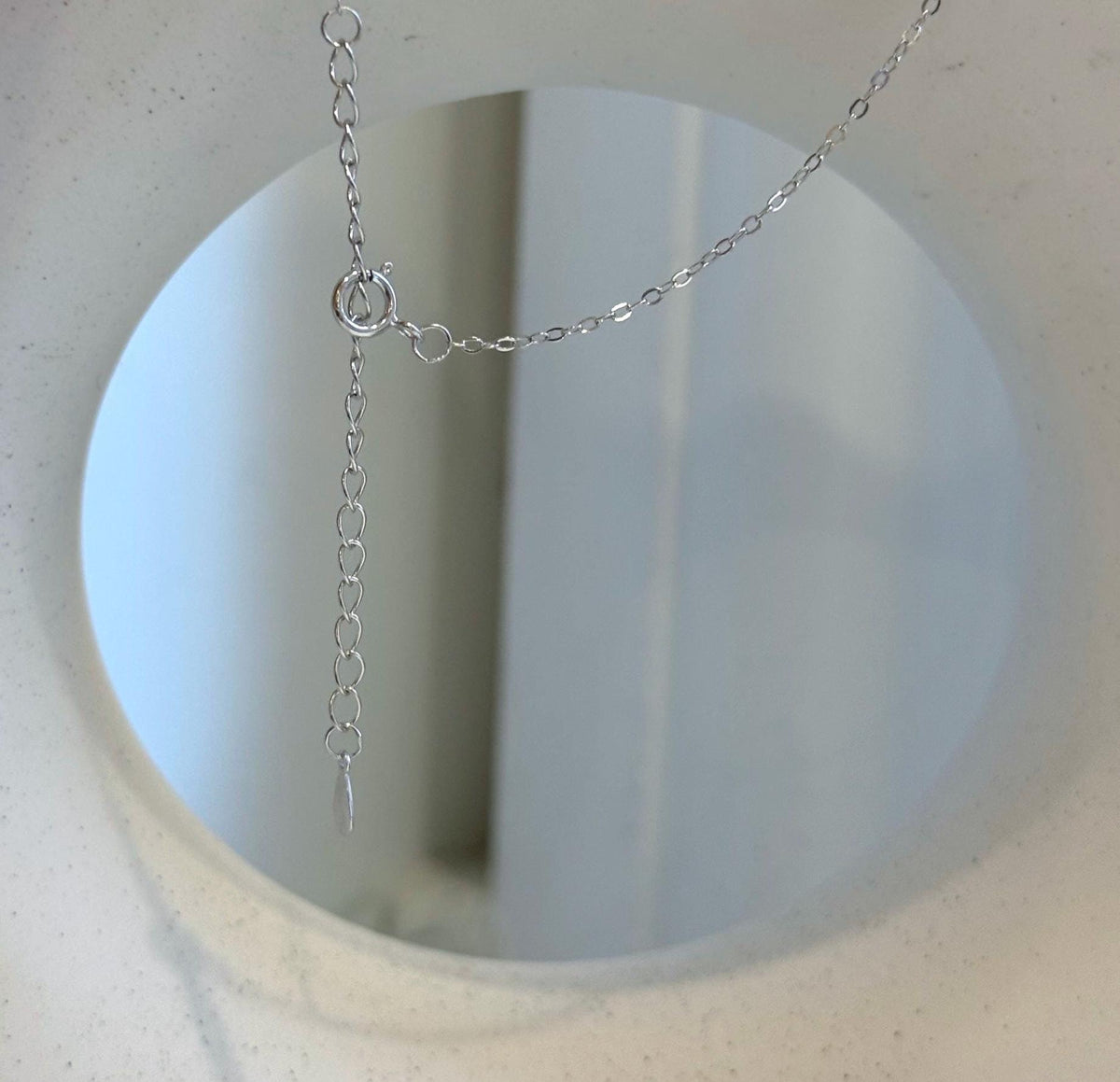 Teardrop Tahitian pearl with mirror luster suspended from a silver knot necklace.