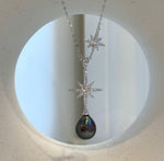 Sterling silver necklace featuring an asymmetrical star detail and a dark pearl drop.