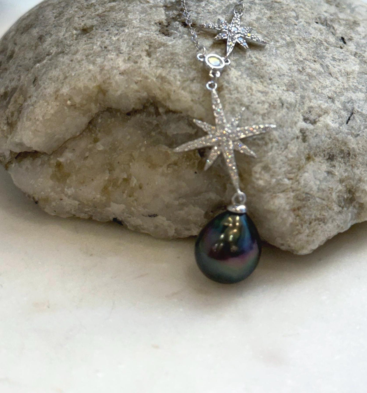 Tahitian pearl necklace displayed against a cream ceramic vase with a circular opening.