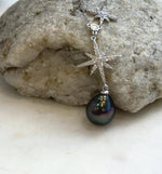 Tahitian pearl necklace displayed against a cream ceramic vase with a circular opening.